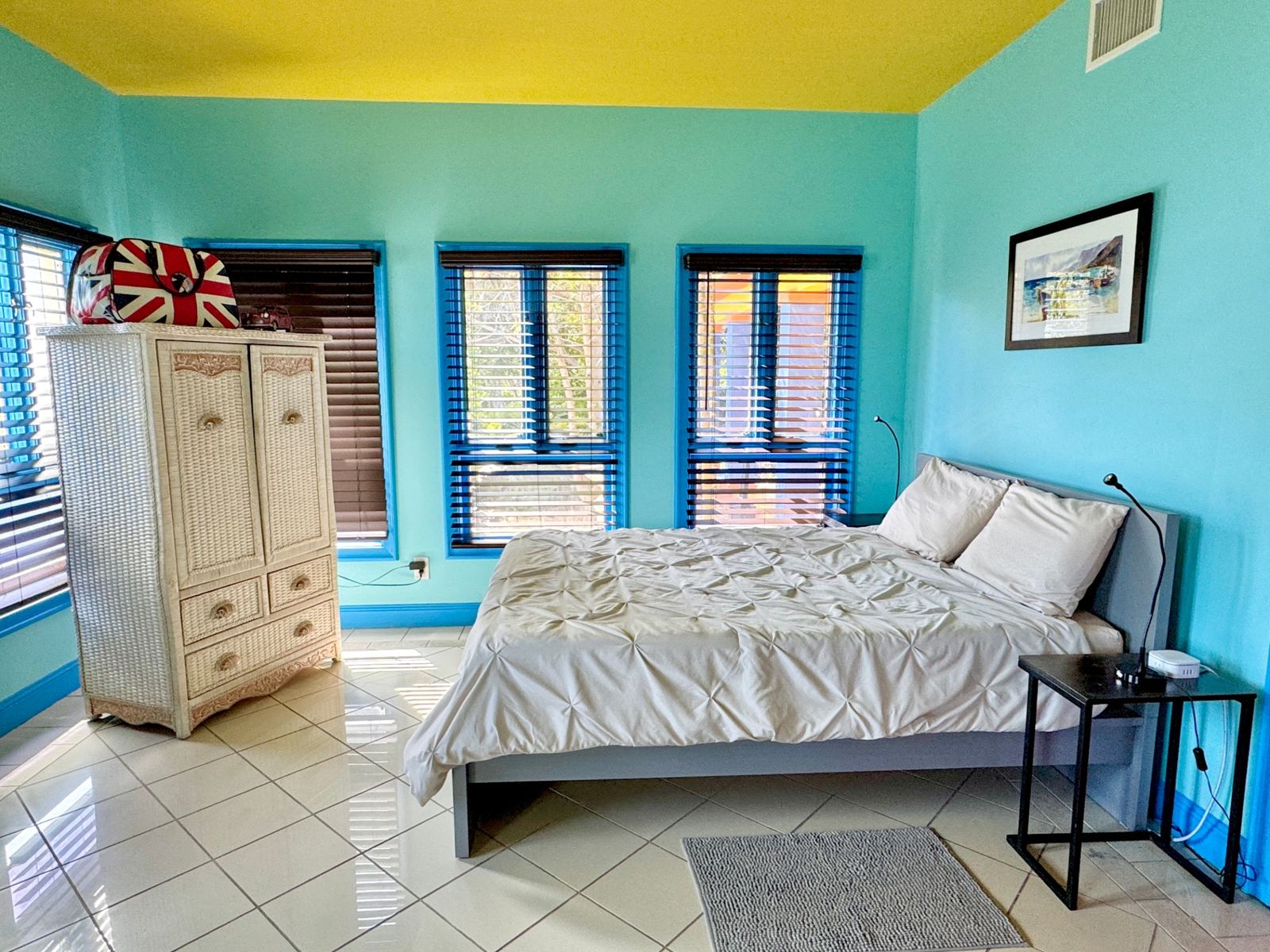 Teal bedroom with yellow ceiling and blue-framed windows
